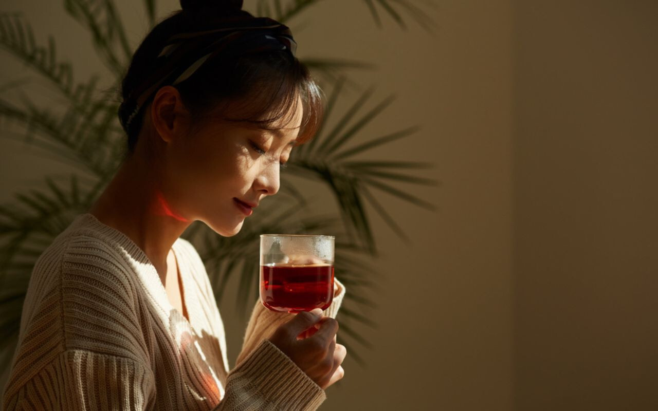 mulher asiática sentada com uma xícara de chá para sinusite na mão