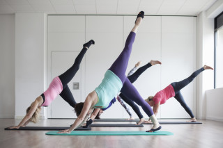 Cinco mulheres fazendo pilates em um estúdio