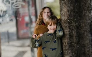 menino e menina apoiados em uma árvore