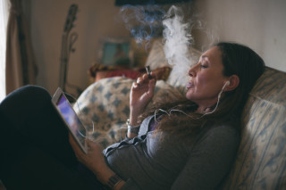 Mulher sentada no sofá fumando