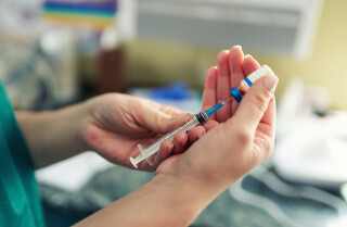 Recorte de imagem de profissional de saúde manuseando uma seringa de vacina