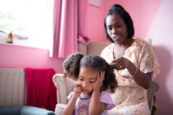 mãe arrumando o cabelo cacheado da filha