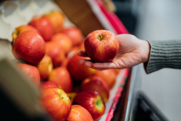 Recorte de imagem de mulher escolhendo uma maçã vermelha no supermercado