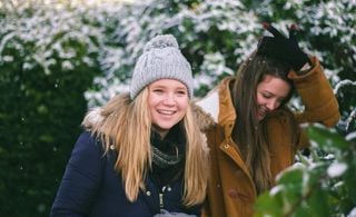 Duas mulheres andando lado a lado em um bosque com neve