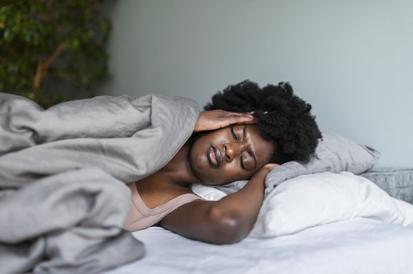 Mulher negra adulta jovem deprimida com dor de cabeça deitada na cama