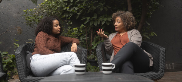 Duas mulheres sentadas conversam e tomam chá