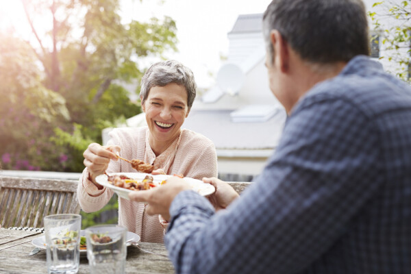 Mulher idosa almoçando no quintal de casa com um homem