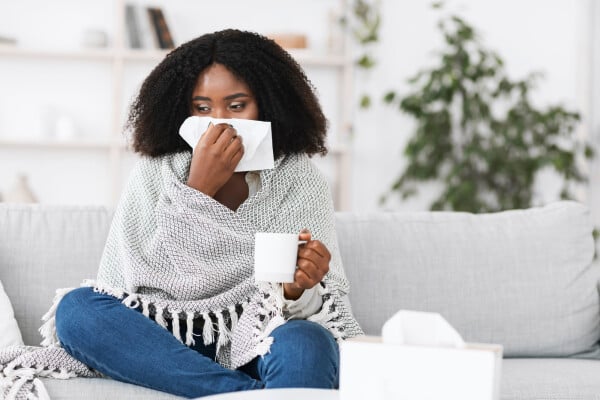 Mulher com gripe assoando o nariz
