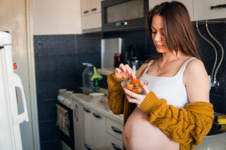 Mulher grávida comendo damasco em um pote pequeno