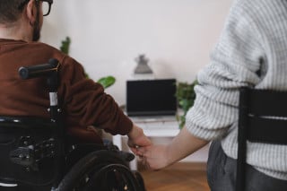 homem em cadeira de rodas segurando a mão da namorada