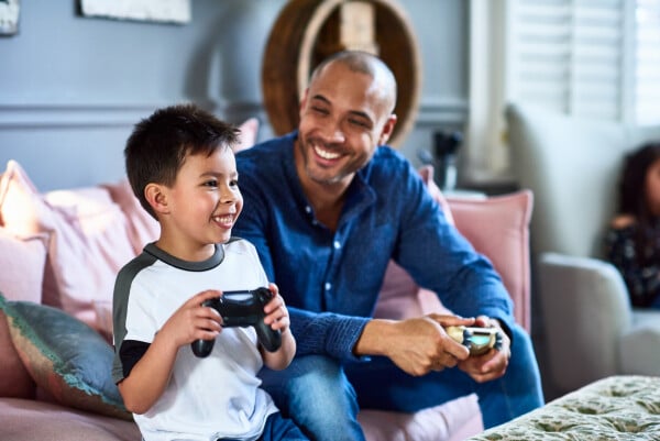 Pai e filho sentados no sofá jogando videogame