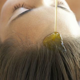 Óleo de rícino sendo aplicado diretamente nos cabelos - Foto: Getty Images