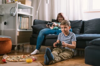 Menino jogando videogame com a mãe