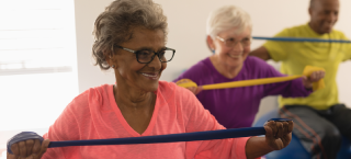 Mulheres idosas fazendo exercício físico com um elástico nas mãos