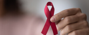 Mão segura laço vermelho símbolo do combate ao HIV