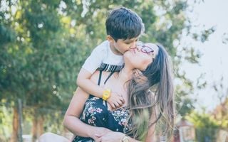 foto de mãe e filho abraçados e dando um beijo na bochecha