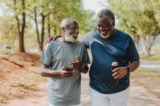 Dois idosos conversando enquanto estão caminhando no parque