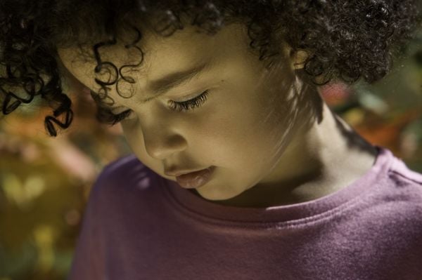 imagem aproximada de uma criança menina usando uma blusa roxa e com os cabelos cacheados