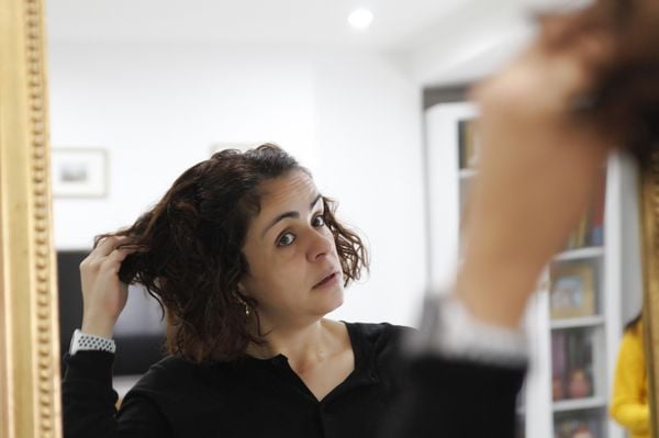 Mulher checando o próprio cabelo em frente ao espelho