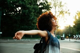 Mulher feliz com os braços abertos na rua