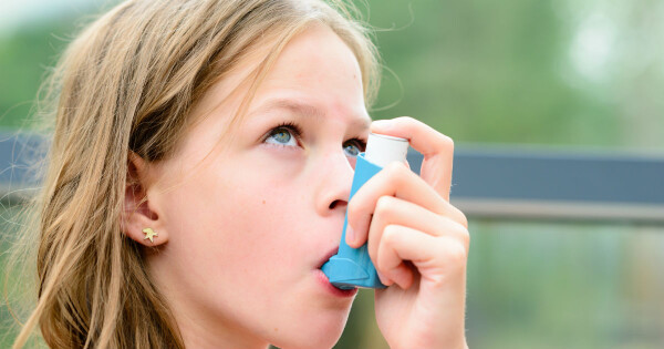 Menina usando inalador de corticoide para tratamento de asma 