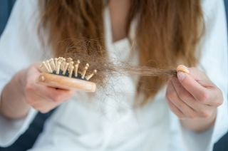 Mulher segurando escola e tufo de cabelo