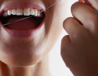 Mulher com fio dental no dente