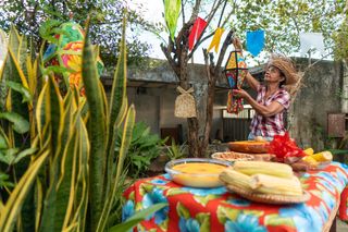 Mulher organizando festa junina perto de mesa com comidas típicas