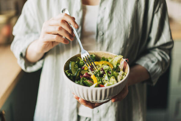 Recorte de imagem de mulher segurando um garfo e uma tigela branca com salada e legumes