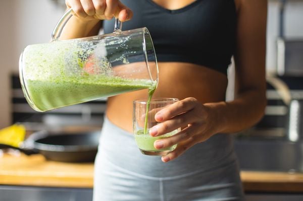 Imagem aproximada de mulher despejando vitamina em copo de vidro