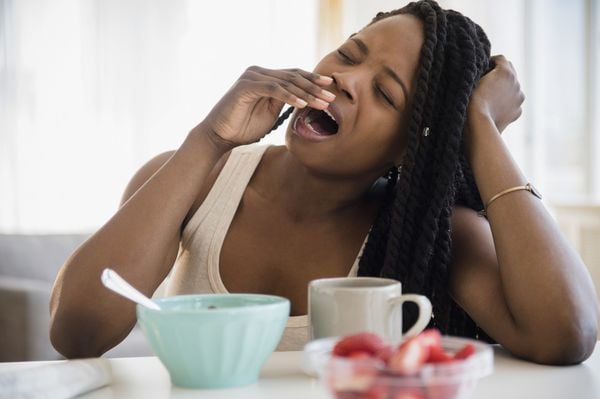 Mulher bocejando durante o café da manhã