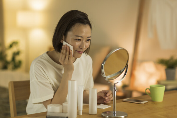 Mulher na frente de espelho pequeno com pano umedecido no rosto durante skincare