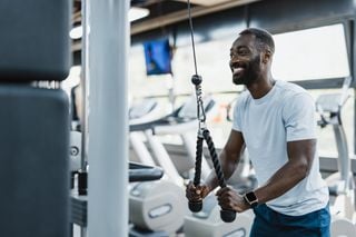 Homem negro fazendo exercício de musculação na academia