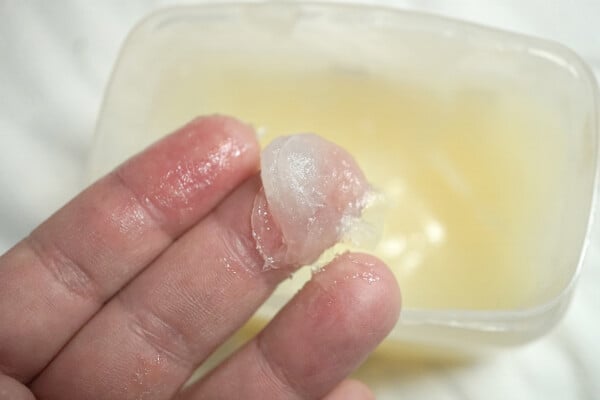 Vaselina nos dedos de uma pessoa, com pote de vaselina embaixo