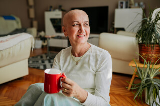 Mulher em tratamento de câncer tomando chá na sala