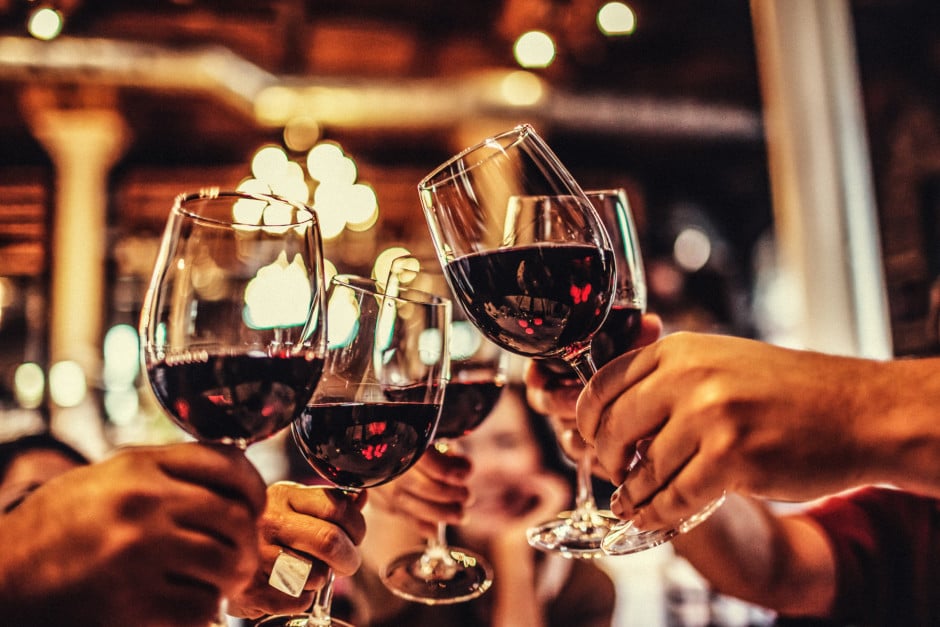 Foto aproximada de pessoas brindando com taças de vinho