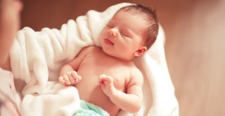 Mãe segurando bebê enrolado na toalha