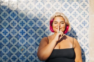 mulher fazendo o símbolo do silêncio com o dedo sobre a boca