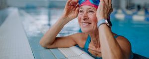 Mulher idosa apoiada na borda de uma piscina