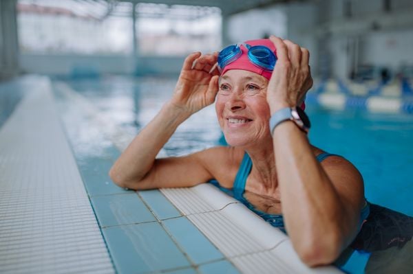 Mulher idosa apoiada na borda de uma piscina