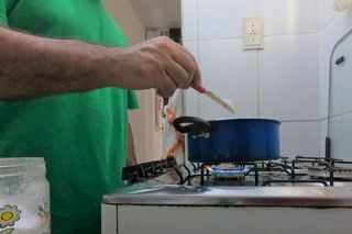 Mão de homem mexendo em panela