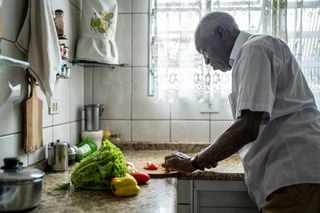 Homem idoso cortando vegetais na cozinha