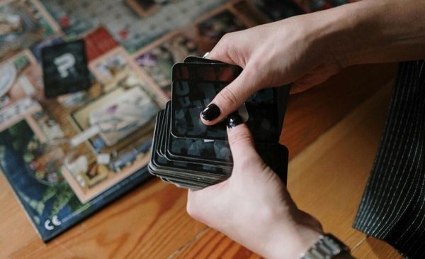 Mãos segurando cartas de um jogo de tabuleiro