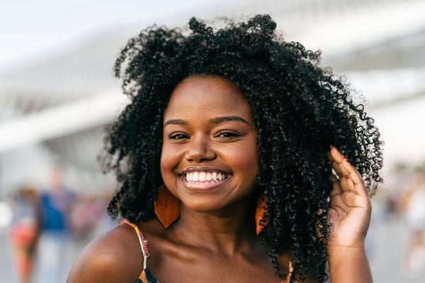 Mulher de cabelos longos e crespos com um sorriso no rosto