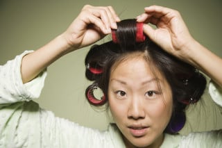 mulher colocando bobes no cabelo