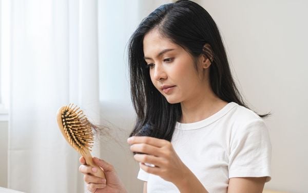 foto de mulher removendo fios de cabelo da escova