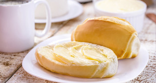 Pão francês com margarina servido ao lado de uma caneca de café