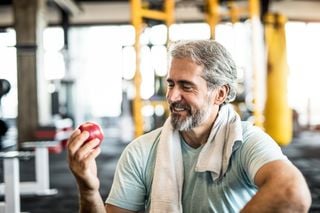 Homem comendo maçã na academia