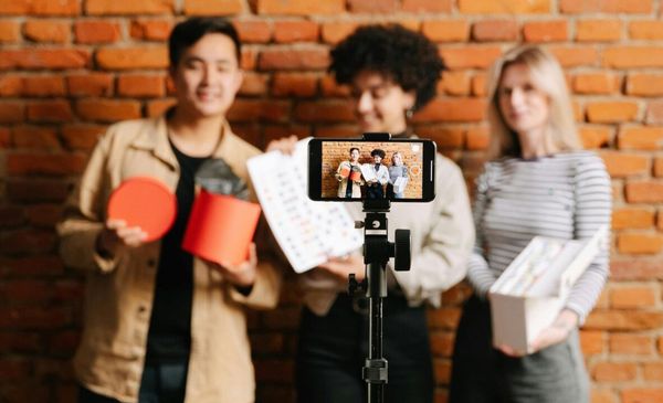 Três jovens desfocados em frente a um celular que está focado