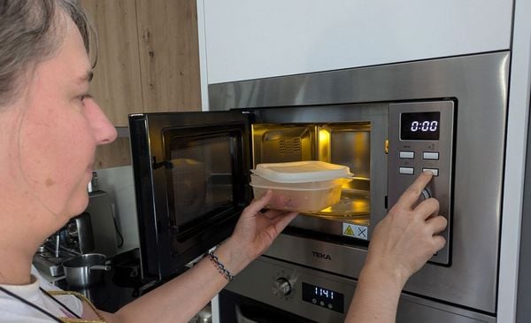 Mulher aquecendo alimento no microondas